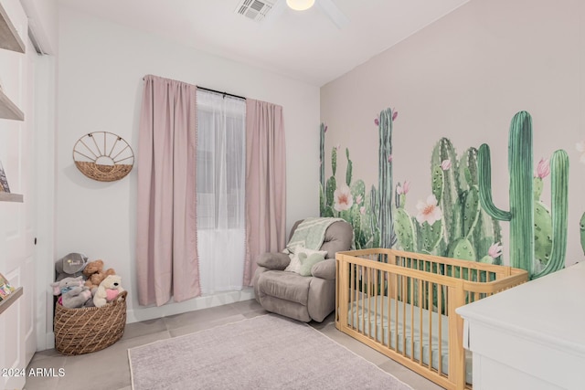 bedroom featuring ceiling fan, light tile patterned floors, and a nursery area