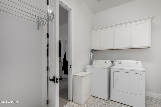 laundry room with washer and dryer, light tile patterned flooring, and cabinets