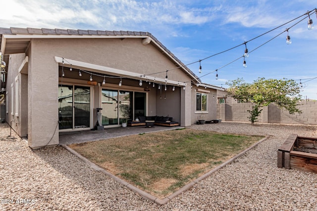 back of property with an outdoor hangout area, a patio area, and a lawn