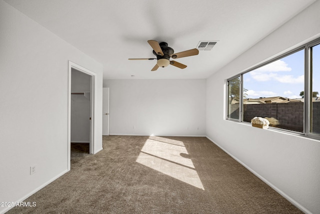 unfurnished bedroom with a closet, a spacious closet, ceiling fan, and carpet flooring