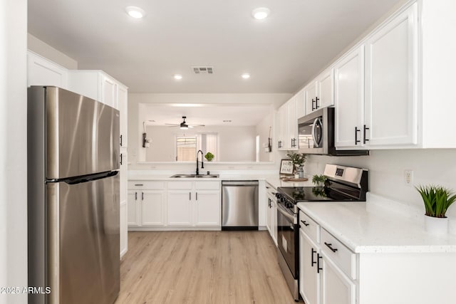 22547 W Pima St, Buckeye, AZ 85326 - kitchen featuring appliances with stainless steel finishes, white cabinetry, ceiling fan, recessed lighting, and light wood-type flooring