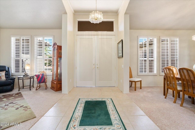 tiled foyer with ornamental molding and a notable chandelier