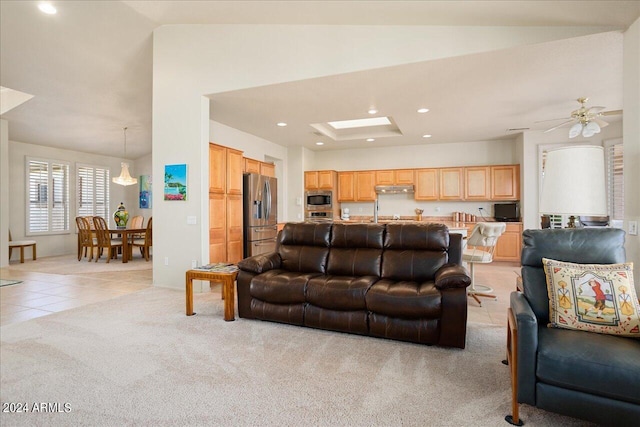 tiled living room with ceiling fan and vaulted ceiling with skylight