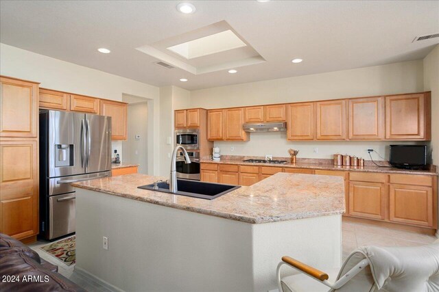 kitchen featuring stainless steel appliances, a center island with sink, light tile flooring, light stone counters, and sink