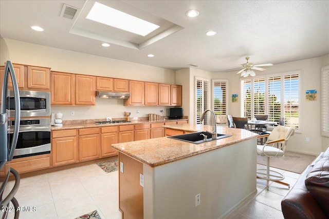 kitchen featuring light tile flooring, stainless steel appliances, sink, a center island with sink, and ceiling fan