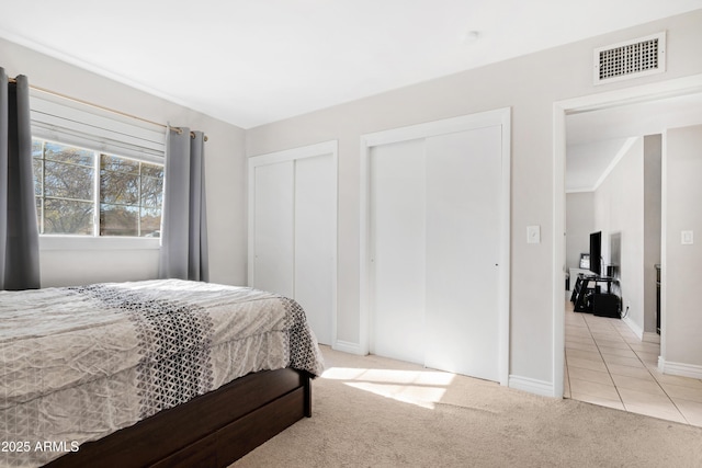 bedroom featuring light carpet and two closets