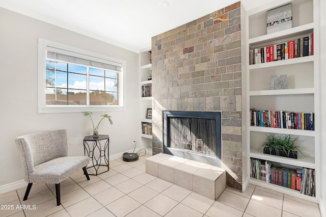 sitting room featuring built in shelves, a tile fireplace, tile patterned flooring, and ornamental molding