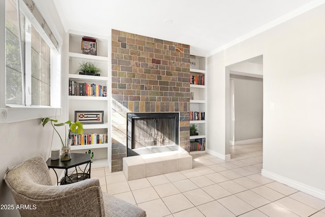 tiled living room featuring built in features, crown molding, and a tiled fireplace