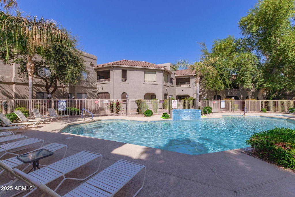 community pool with fence and a patio