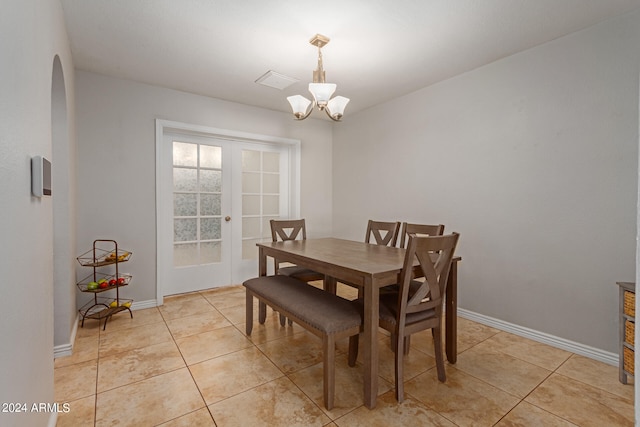 tiled dining space with a chandelier and french doors