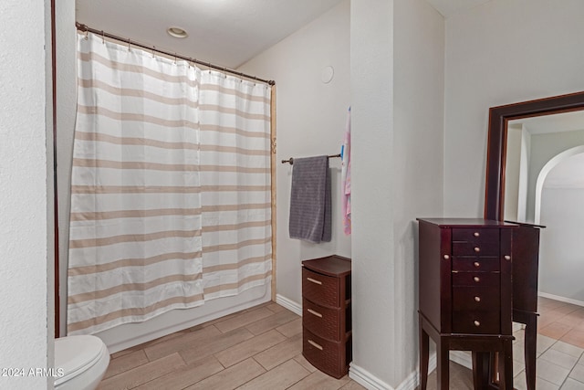 bathroom with shower / bath combination with curtain and toilet