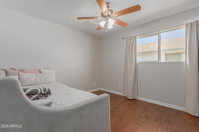 bedroom with ceiling fan, a textured ceiling, and dark hardwood / wood-style flooring