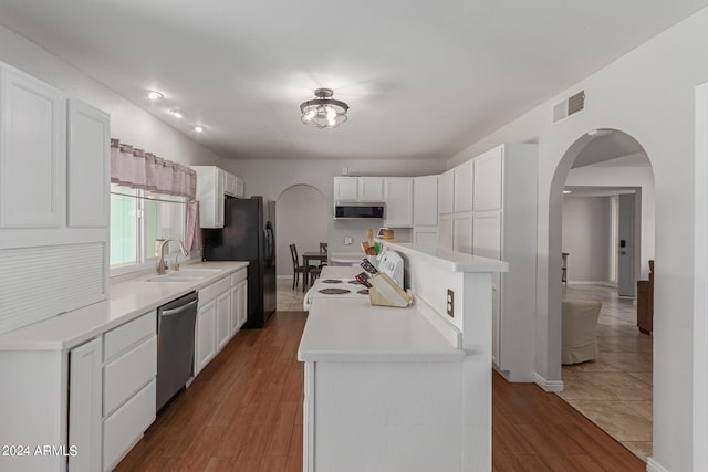 kitchen featuring appliances with stainless steel finishes, hardwood / wood-style floors, white cabinets, and sink