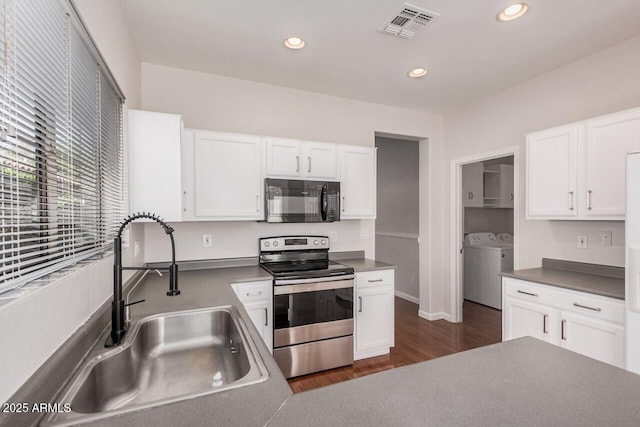 40713 N Courage Trl, Anthem, AZ 85086 - kitchen with black microwave, stainless steel range with electric stovetop, washing machine and dryer, white cabinetry, and dark wood finished floors