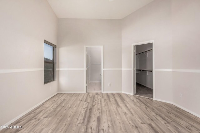 40713 N Courage Trl, Anthem, AZ 85086 - unfurnished bedroom featuring wood finished floors, a spacious closet, a closet, and high vaulted ceiling