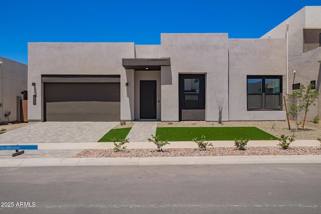 view of front facade with an attached garage, stucco siding, and driveway