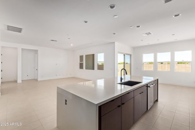 kitchen with a sink, a center island with sink, open floor plan, light countertops, and recessed lighting