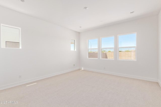 unfurnished room featuring light colored carpet and baseboards