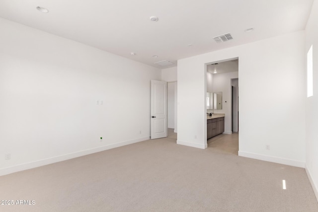 unfurnished bedroom with light carpet, baseboards, and connected bathroom
