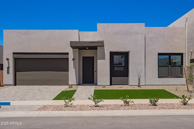 view of front of home with an attached garage, stucco siding, and driveway