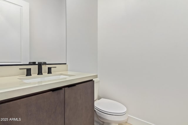 bathroom with baseboards, toilet, and vanity