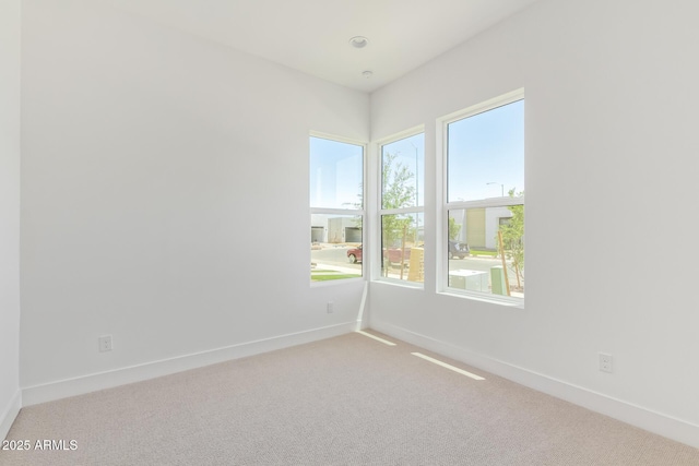 empty room featuring plenty of natural light, carpet flooring, and baseboards