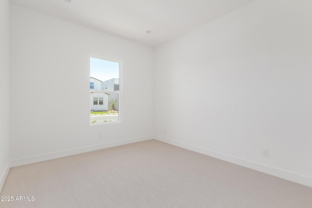 spare room with light colored carpet and baseboards
