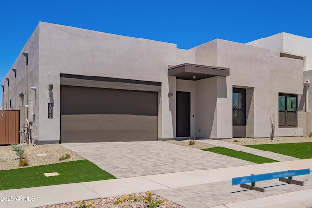 view of front of house featuring stucco siding, an attached garage, and driveway