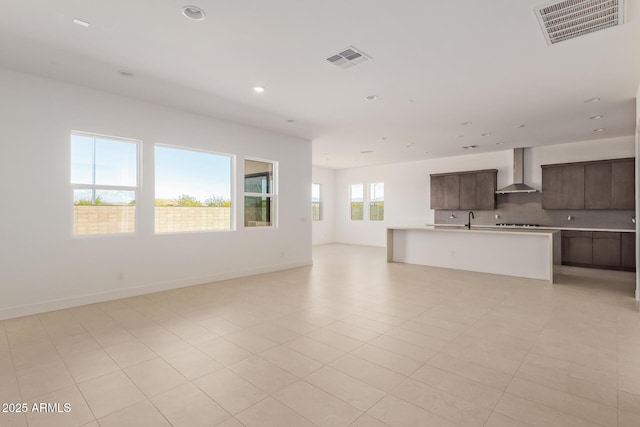 unfurnished living room with recessed lighting, a sink, and baseboards