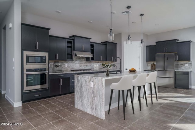 kitchen featuring visible vents, a breakfast bar area, appliances with stainless steel finishes, dark cabinets, and under cabinet range hood