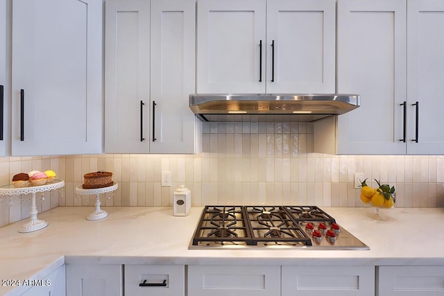 kitchen featuring backsplash, white cabinetry, light stone counters, and stainless steel gas stovetop