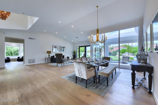 dining area with light hardwood / wood-style flooring, lofted ceiling, and a notable chandelier