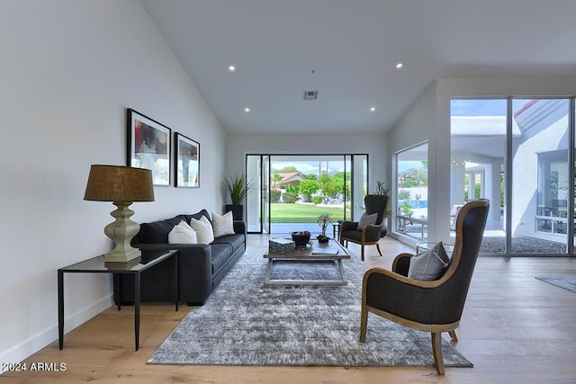 living room featuring a wealth of natural light, high vaulted ceiling, and hardwood / wood-style flooring