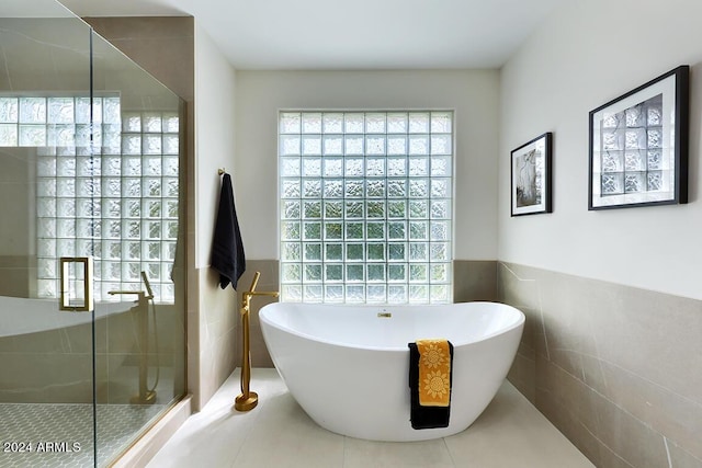 bathroom with tile patterned floors, tile walls, and plus walk in shower