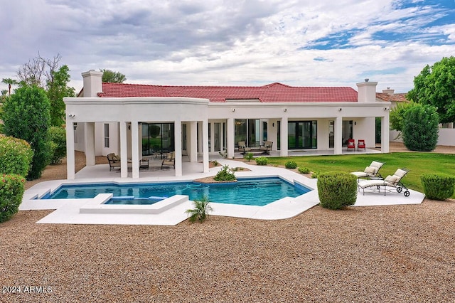 rear view of house featuring a patio and a pool with hot tub