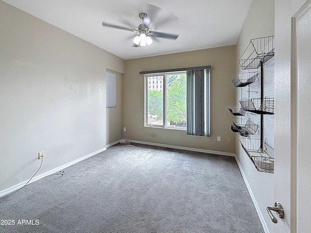 carpeted empty room featuring ceiling fan and baseboards