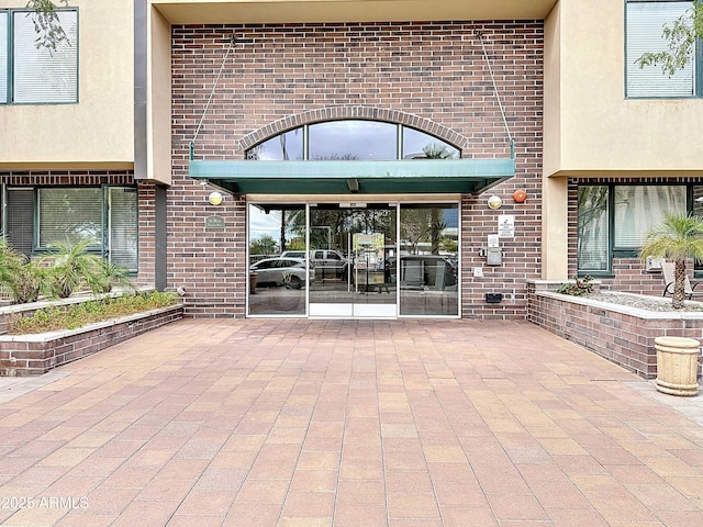 doorway to property with a patio area and brick siding