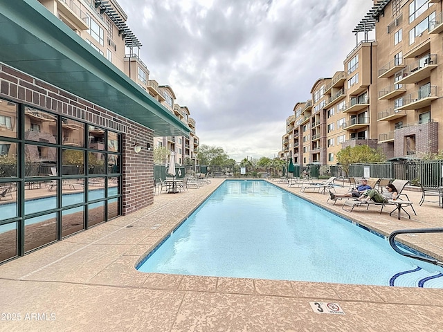 pool with a patio area and fence