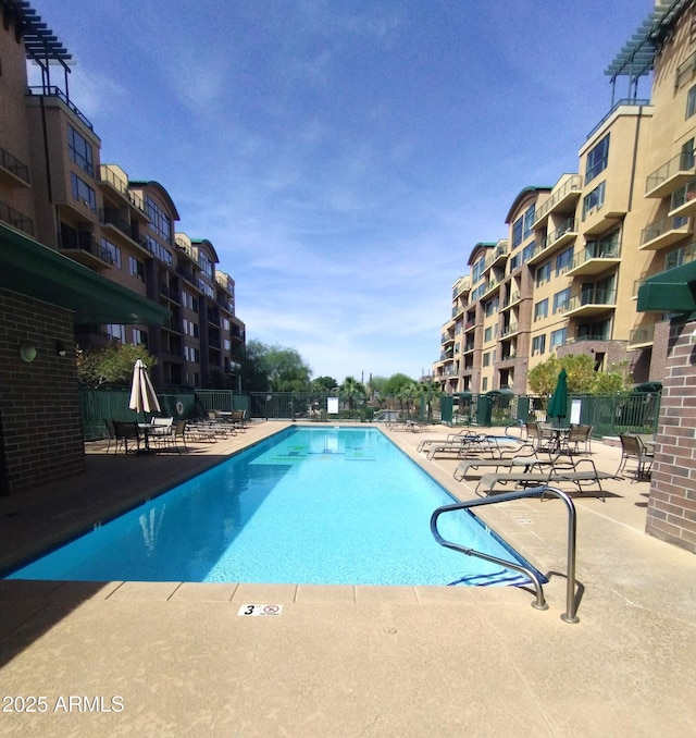 community pool with a patio area and fence