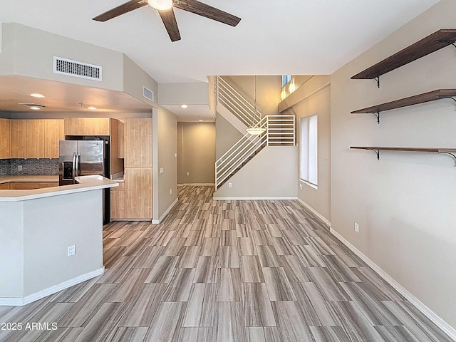 kitchen featuring stainless steel fridge with ice dispenser, visible vents, decorative backsplash, and a ceiling fan