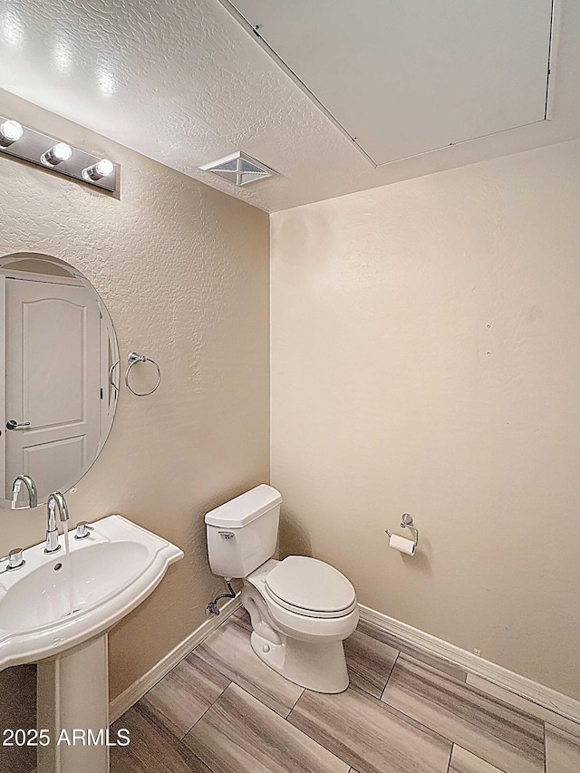 bathroom with toilet, baseboards, visible vents, and wood tiled floor