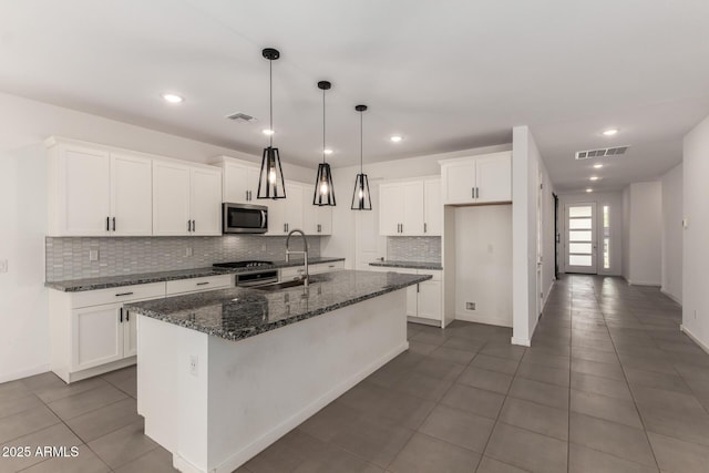 22568 E Rosa Rd, Queen Creek, AZ 85142 - kitchen featuring stainless steel microwave, a sink, tasteful backsplash, a kitchen island with sink, and white cabinetry
