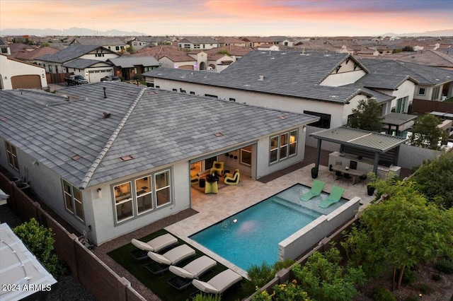 back house at dusk with a patio area and a fenced in pool