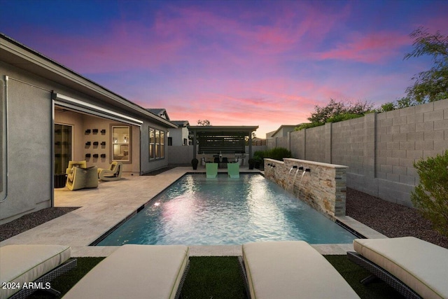 pool at dusk featuring a patio area and pool water feature