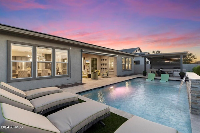 pool at dusk with ceiling fan, a patio area, pool water feature, and an outdoor living space