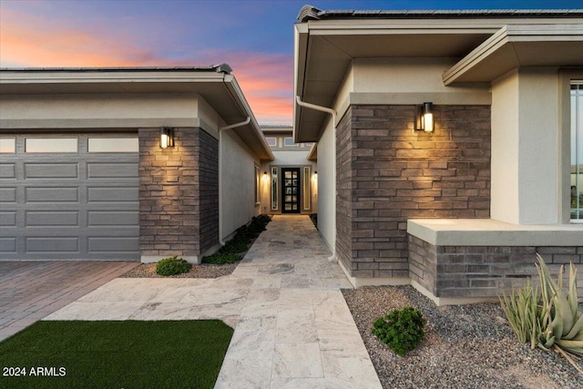 exterior entry at dusk featuring a garage