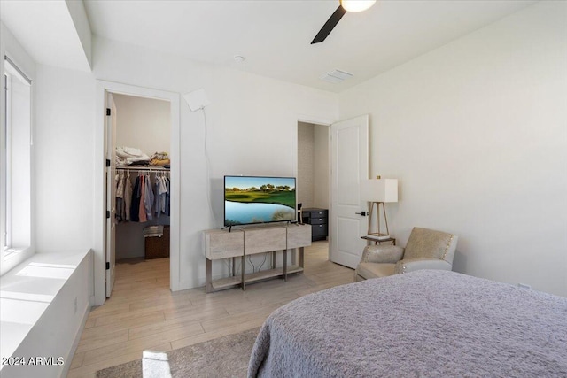 bedroom with a closet, ceiling fan, light hardwood / wood-style flooring, and a walk in closet