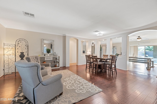 dining room featuring ornamental molding, arched walkways, visible vents, and wood finished floors