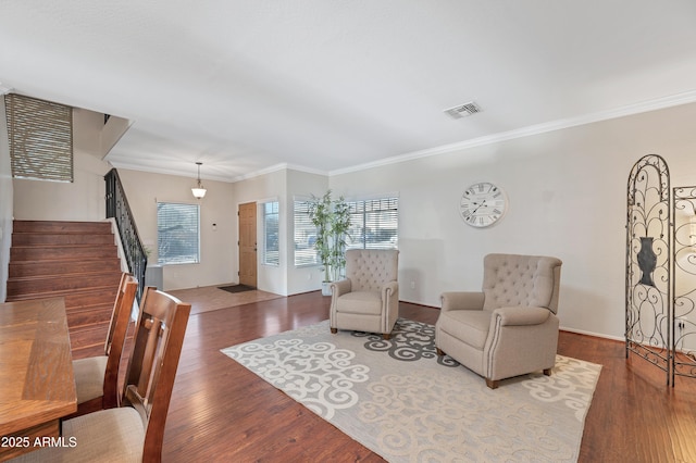 living area with crown molding, stairs, visible vents, and wood finished floors