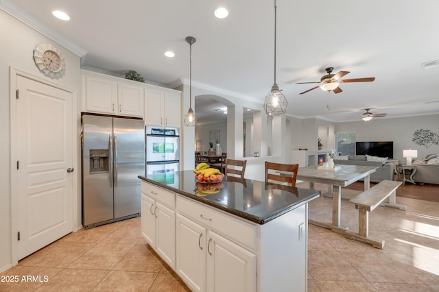 kitchen with dark countertops, light tile patterned floors, appliances with stainless steel finishes, and arched walkways